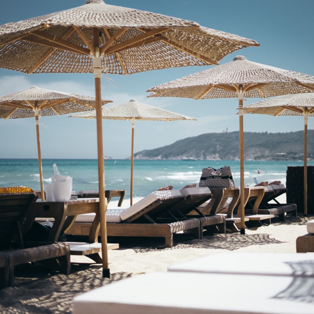 Selective wide shot brown wooden loungers parasols by beach