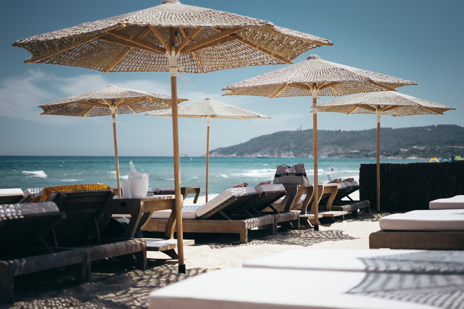 Selective wide shot brown wooden loungers parasols by beach