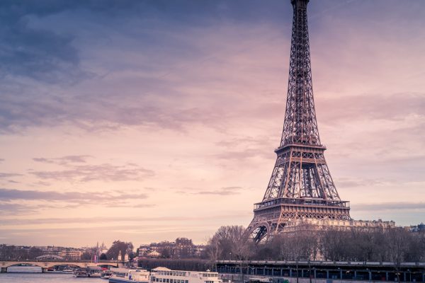 Beautiful Wide Shot Of Eiffel Tower In Paris Surrounded By Water With Ships Under The Colorful Sky